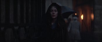 Movie still from “Valmont” (1989), directed by Milos Forman – A woman in a black robe holding an umbrella; Medium shot, Low angle