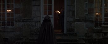 Movie still from “Valmont” (1989), directed by Milos Forman – A person standing in front of a door at night; Wide shot, Over the shoulder angle