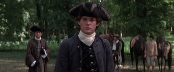 Movie still from “Valmont” (1989), directed by Milos Forman – A young man in a pirate's hat stands in front of a group of horses; Medium shot, Over the shoulder angle