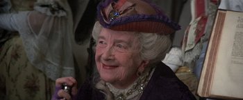 Movie still from “Valmont” (1989), directed by Milos Forman – An older woman wearing a hat and a necklace; Close Up shot, Over the shoulder angle