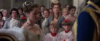 Movie still from “Valmont” (1989), directed by Milos Forman – A group of people standing around each other in a room; Medium shot, Over the shoulder angle