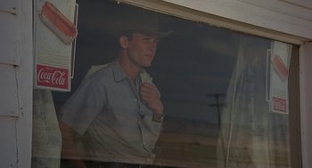 Movie still from “Vanishing Point” (1971), directed by Richard C. Sarafian – A man wearing a cowboy hat standing in front of a window; Medium shot, Low angle