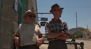 Movie still from “Vanishing Point” (1971), directed by Richard C. Sarafian – A couple of men standing next to each other on a street; Medium shot, Low angle