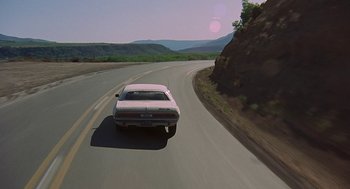 Movie still from “Vanishing Point” (1971), directed by Richard C. Sarafian – A car driving down a curvy road near a mountain range; Extreme Wide shot, High angle