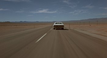 Movie still from “Vanishing Point” (1971), directed by Richard C. Sarafian – A car driving down the middle of a road; Extreme Wide shot, High angle