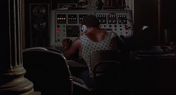 Movie still from “Vanishing Point” (1971), directed by Richard C. Sarafian – A man sitting in front of a computer with headphones on; Medium shot, Low angle