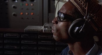 Movie still from “Vanishing Point” (1971), directed by Richard C. Sarafian – A man wearing headphones and glasses is listening to music; Close Up shot, Low angle
