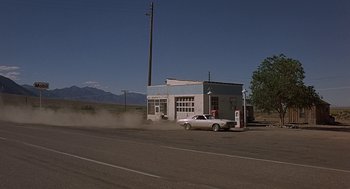 Movie still from “Vanishing Point” (1971), directed by Richard C. Sarafian – An old white car parked in front of a gas station; Extreme Wide shot, Low angle
