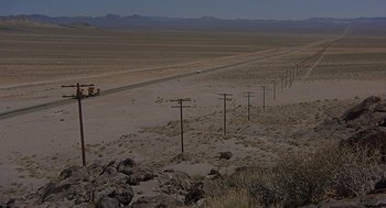 Movie still from “Vanishing Point” (1971), directed by Richard C. Sarafian – A truck driving down a dirt road in the middle of the desert; Extreme Wide shot, High angle
