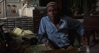 Movie still from “Vanishing Point” (1971), directed by Richard C. Sarafian – A man sitting in front of a microphone in a room; Close Up shot, Low angle