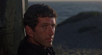 Movie still from “Vanishing Point” (1971), directed by Richard C. Sarafian – A person wearing a black shirt near a body of water; Close Up shot, Over the shoulder angle