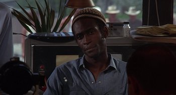 Movie still from “Vanishing Point” (1971), directed by Richard C. Sarafian – A man wearing a hat sitting in front of a window; Close Up shot, Over the shoulder angle