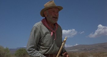 Movie still from “Vanishing Point” (1971), directed by Richard C. Sarafian – An old man in a cowboy hat holding a wooden stick; Medium shot, Low angle