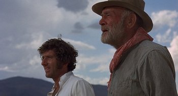 Movie still from “Vanishing Point” (1971), directed by Richard C. Sarafian – Two men standing next to each other on a cloudy day; Close Up shot, Low angle