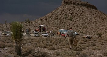 Movie still from “Vanishing Point” (1971), directed by Richard C. Sarafian – A man walking in the middle of the desert; Extreme Wide shot, Over the shoulder angle