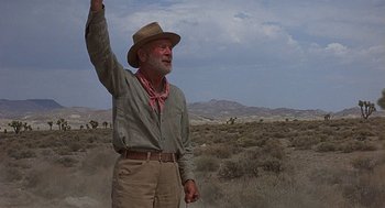 Movie still from “Vanishing Point” (1971), directed by Richard C. Sarafian – An old man in a cowboy hat and a cowboy hat waving; Medium shot, Low angle