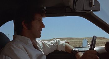 Movie still from “Vanishing Point” (1971), directed by Richard C. Sarafian – A man sitting in the driver's seat of a car looking out the window; Close Up shot, Low angle
