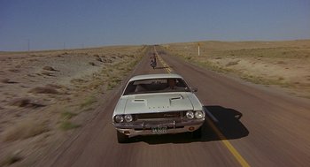Movie still from “Vanishing Point” (1971), directed by Richard C. Sarafian – A car driving down the middle of a road; Wide shot, High angle