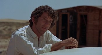 Movie still from “Vanishing Point” (1971), directed by Richard C. Sarafian – A man sitting at a table with his arms folded on top of it; Close Up shot, Low angle