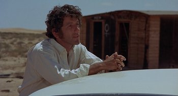 Movie still from “Vanishing Point” (1971), directed by Richard C. Sarafian – A man sitting on the hood of a white car; Medium shot, Low angle