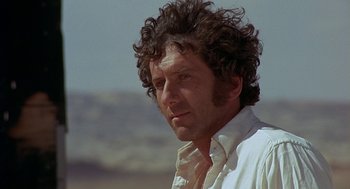 Movie still from “Vanishing Point” (1971), directed by Richard C. Sarafian – A person with curly hair wearing a white shirt; Close Up shot, Low angle