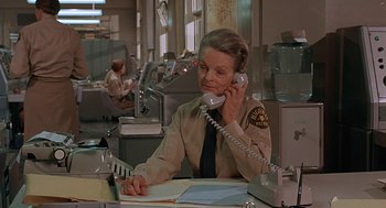 Movie still from “Vanishing Point” (1971), directed by Richard C. Sarafian – A woman sitting at a desk talking on a phone; Medium shot, High angle