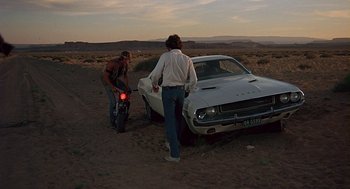 Movie still from “Vanishing Point” (1971), directed by Richard C. Sarafian – Two men standing next to an old white car in the middle of the desert; Wide shot, High angle