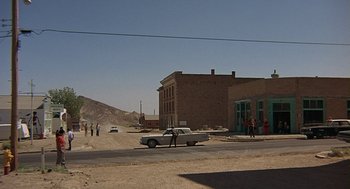Movie still from “Vanishing Point” (1971), directed by Richard C. Sarafian – An old white car parked on the side of the road; Extreme Wide shot, Over the shoulder angle