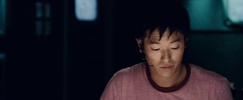 Movie still from “Vantage Point” (2008), directed by Pete Travis – A young man with his eyes closed looking down at the ground; Close Up shot, High angle