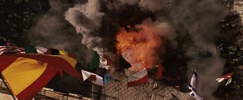 Movie still from “Vantage Point” (2008), directed by Pete Travis – An image of an explosion in a building with flags of different countries; Wide shot, Overhead angle