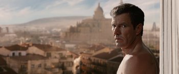 Movie still from “Vantage Point” (2008), directed by Pete Travis – A man standing in front of an old city; Close Up shot, Low angle