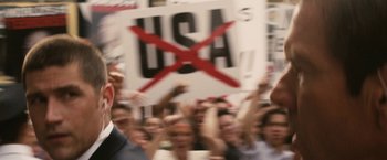Movie still from “Vantage Point” (2008), directed by Pete Travis – A group of people holding up signs in a crowd; Close Up shot, Over the shoulder angle