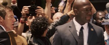 Movie still from “Vantage Point” (2008), directed by Pete Travis – A man in a crowd of people with his hands in the air; Close Up shot, Over the shoulder angle