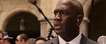 Movie still from “Vantage Point” (2008), directed by Pete Travis – A man in a gray suit and a white tie; Close Up shot, Over the shoulder angle