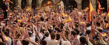 Movie still from “Vantage Point” (2008), directed by Pete Travis – A large crowd of people waving flags in the air; Extreme Wide shot, High angle