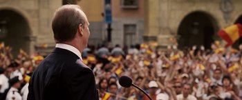 Movie still from “Vantage Point” (2008), directed by Pete Travis – A man is speaking to a crowd of people; Medium shot, Over the shoulder angle
