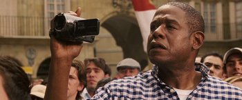 Movie still from “Vantage Point” (2008), directed by Pete Travis – A man holding up a video camera in front of a crowd of people; Close Up shot, Low angle