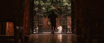 Movie still from “Vantage Point” (2008), directed by Pete Travis – A man walking through a gated entrance to a building; Wide shot, High angle