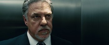 Movie still from “Vantage Point” (2008), directed by Pete Travis – An older man wearing a suit and tie in an elevator; Close Up shot, Low angle