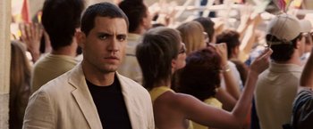 Movie still from “Vantage Point” (2008), directed by Pete Travis – A man standing in front of a group of people; Close Up shot, Over the shoulder angle