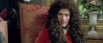 Movie still from “Vatel” (2000), directed by Roland Joffé – A man in a red jacket with long hair and a mustache; Close Up shot, Over the shoulder angle
