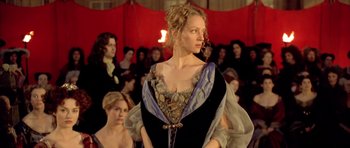 Movie still from “Vatel” (2000), directed by Roland Joffé – A woman in a black and blue dress standing in front of a group of people; Medium shot, Over the shoulder angle