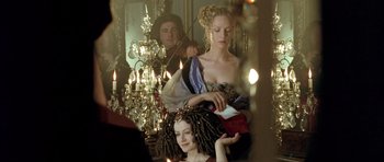Movie still from “Vatel” (2000), directed by Roland Joffé – A woman is sitting in front of a mirror while a man is standing next to her; Medium shot, Over the shoulder angle