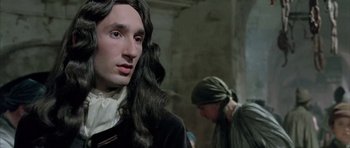 Movie still from “Vatel” (2000), directed by Roland Joffé – A man with long black hair wearing a wig; Close Up shot, Over the shoulder angle
