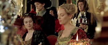Movie still from “Vatel” (2000), directed by Roland Joffé – A woman in a green dress sitting in front of other people; Close Up shot, Over the shoulder angle