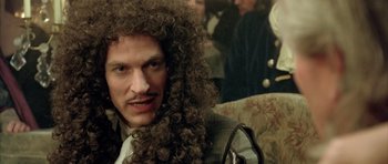 Movie still from “Vatel” (2000), directed by Roland Joffé – A man with long hair and a mustache is sitting; Close Up shot, Over the shoulder angle