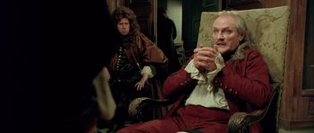 Movie still from “Vatel” (2000), directed by Roland Joffé – A man sitting on a chair in front of another man; Medium shot, Over the shoulder angle