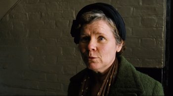 Movie still from “Vera Drake” (2004), directed by Mike Leigh – An older woman wearing a black hat and a green jacket; Close Up shot, Low angle