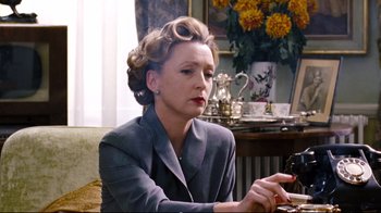 Movie still from “Vera Drake” (2004), directed by Mike Leigh – An older woman sitting at a table looking at her phone; Medium shot, Low angle