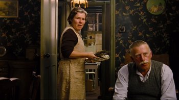Movie still from “Vera Drake” (2004), directed by Mike Leigh – An older woman standing in front of an older man; Medium shot, Over the shoulder angle